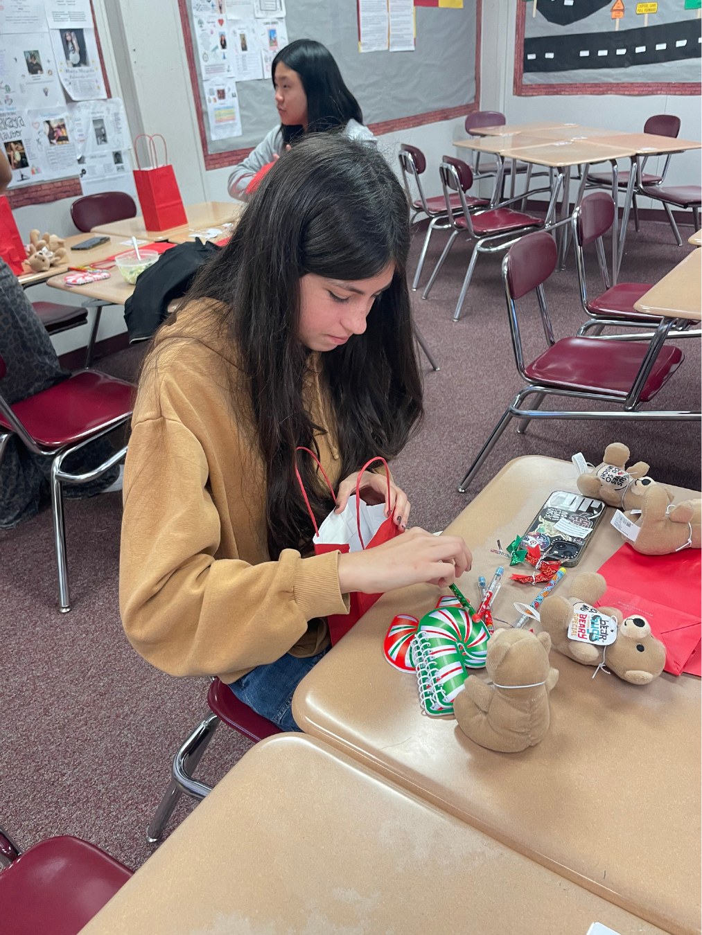 A student creating holiday tags for foster children